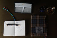 A6 Blank Pocket Notebook — open, blank pages and slate blue ribbon